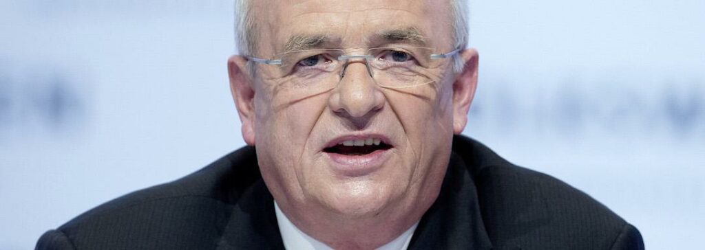 En man i kostym och slips talar på en konferens. (AI text)