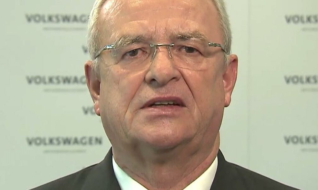 En man i kostym och slips pratar mot kameran. (AI text)