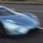 En blå sportbil kör nerför en väg. (AI text)