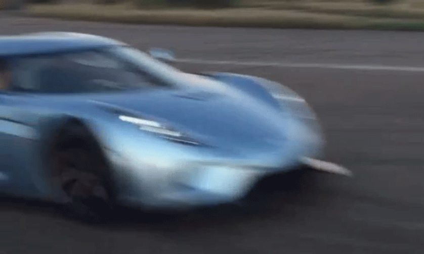 En blå sportbil kör nerför en väg. (AI text)