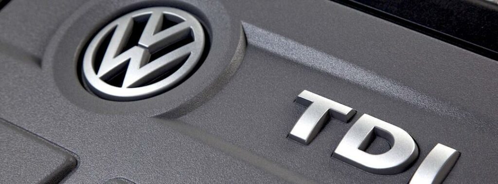 En Volkswagen TDI-logotyp på motorn av en bil. (AI text)