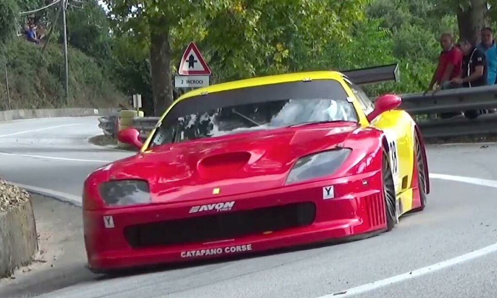 En röd och gul sportbil kör nerför en backe. (AI text)