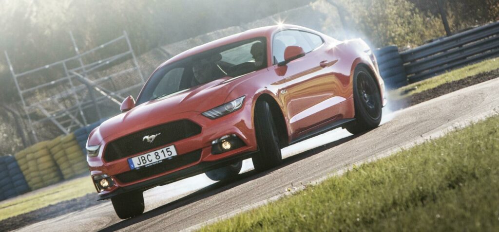 En röd Ford Mustang GT kör på en bana. (AI text)