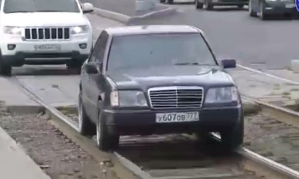 En bil kör ner längs en järnvägsspår. (AI text)