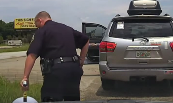 En polis befäster en däck på en bil. (AI text)