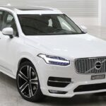 En vit Volvo XC90 står parkerad i en garage. (AI text)
