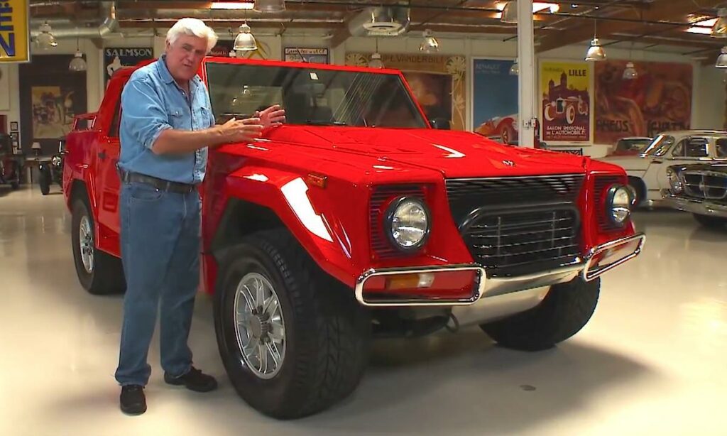 En man står bredvid en röd SUV i en garage. (AI text)