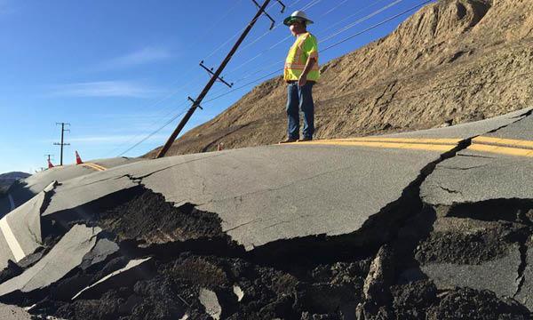En arbetare står på en skadad väg som har skadats av en jordrutsch. (AI text)