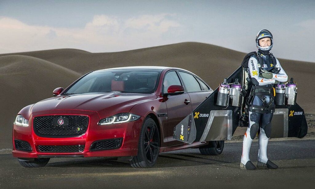 En man i kostym står bredvid en Jaguar XJ. (AI text)