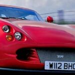 En röd sportbil kör nerför en väg. (AI text)