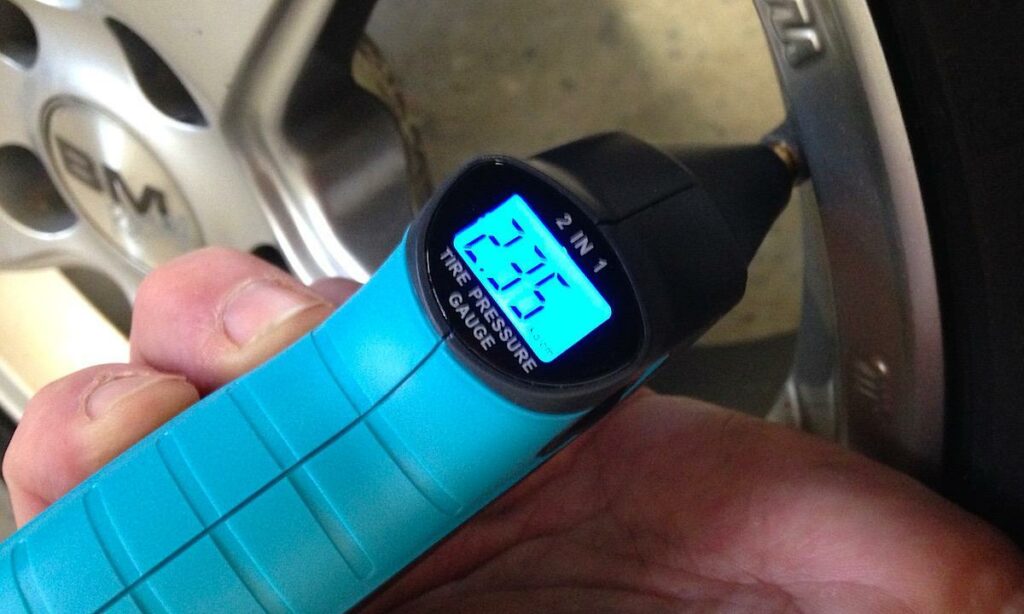 En person håller på att mäta trycket i en däckluftmätare. (AI text)