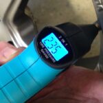 En person håller på att mäta trycket i en däckluftmätare. (AI text)