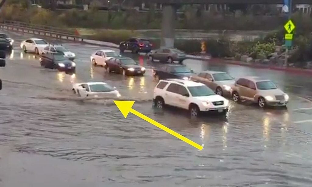 En bil är parkerad på en översvämmad gata. (AI text)