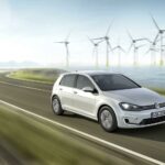 En vit Volkswagen Golf E - EV kör längs en kurvig väg. (AI text)