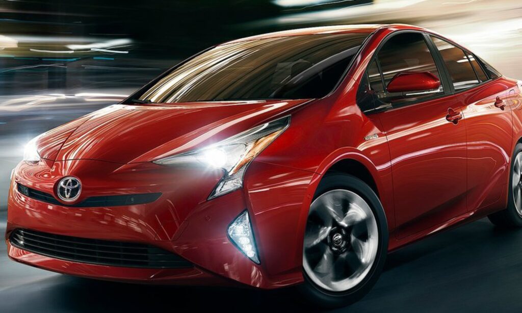 En röd Toyota Prius körs nerför en stadsgata. (AI text)