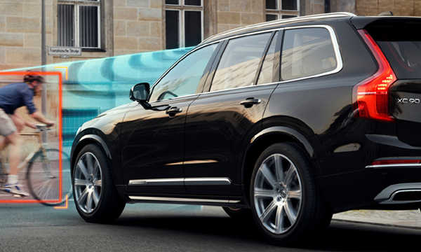 Volvo XC90-fordonet kör nedför gatan med en cykelriktad person i framsätet. (AI text)