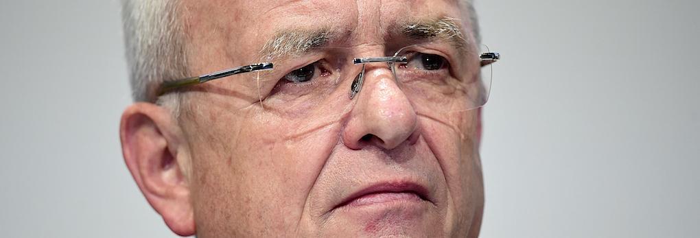 En man i kostym och slips tittar på kameran. (AI text)