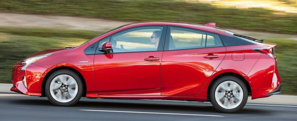 En röd Toyota Prius kör ner en väg. (AI text)