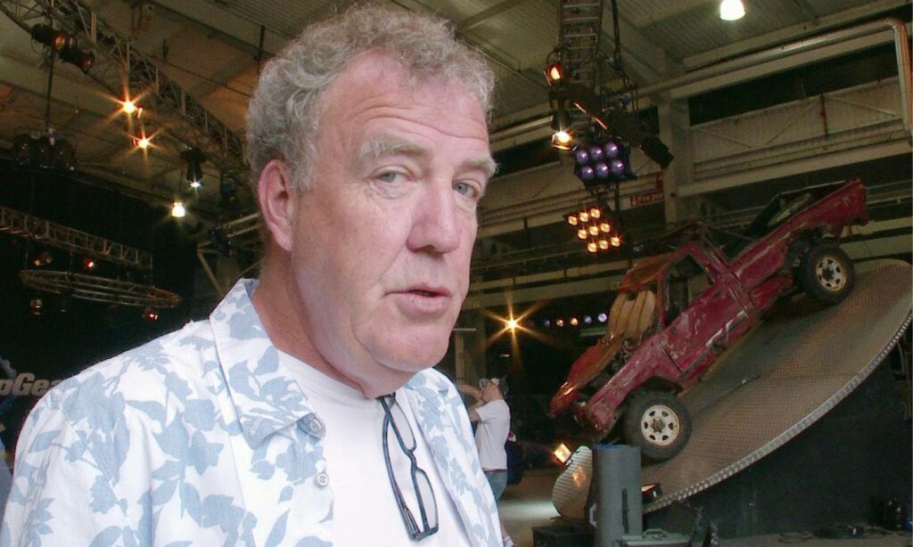 En man i en hawaiiskjorta står framför en bil. (AI text)