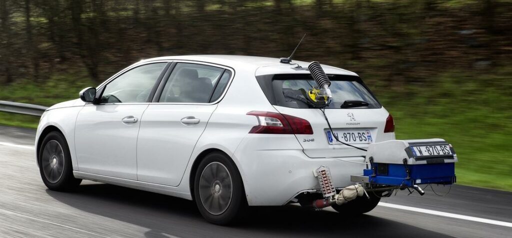 En vit bil körer nedför en väg med en släp upphängd bakom den. (AI text)