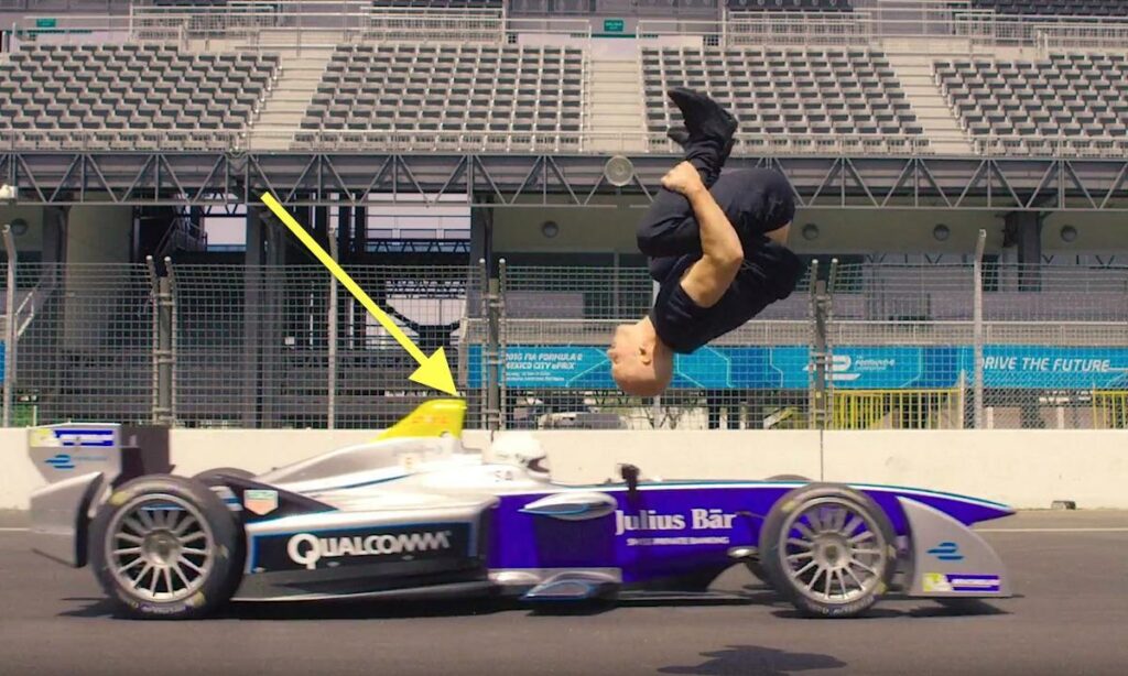 En man utför en baklyft på en racerbil. (AI text)