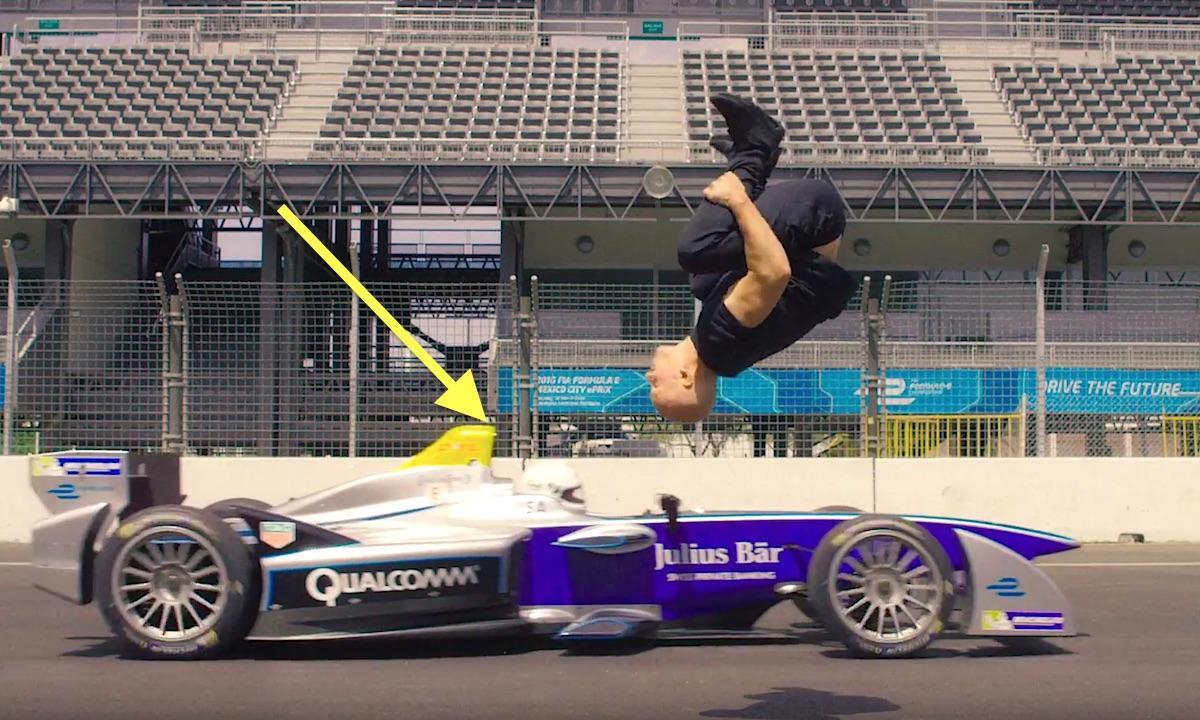 En man utför en baklyft på en racerbil. (AI text)