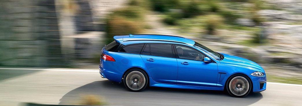 En blå Jaguar XF kör nedför en bergsväg. (AI text)