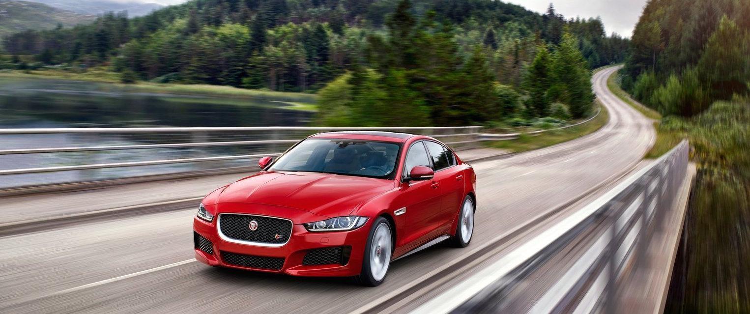 En röd Jaguar XF körs nedför en bergsväg. (AI text)