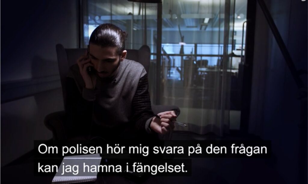En man pratar i telefon i en mörk rum. (AI text)