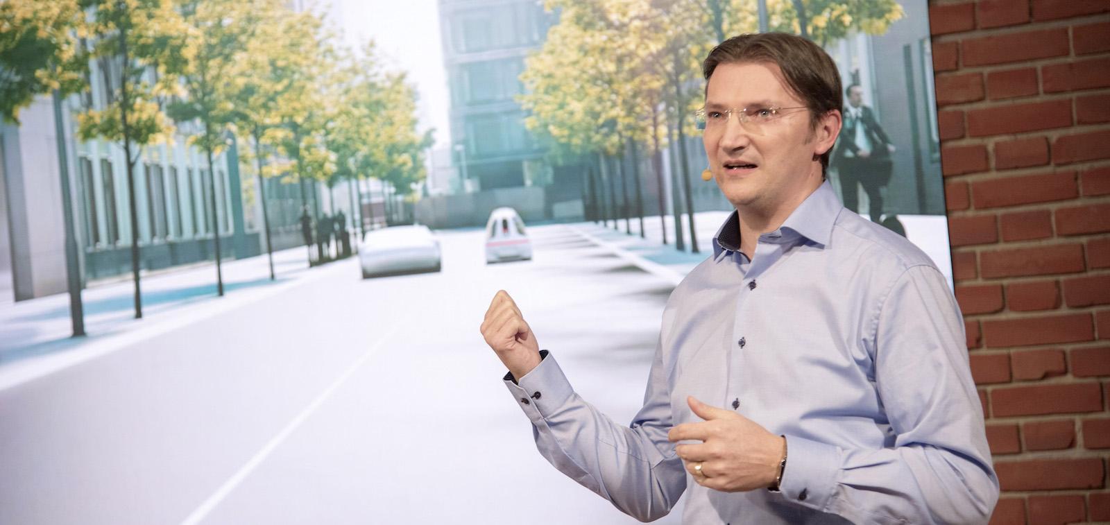 En man står framför en projicerings-skärm. (AI text)