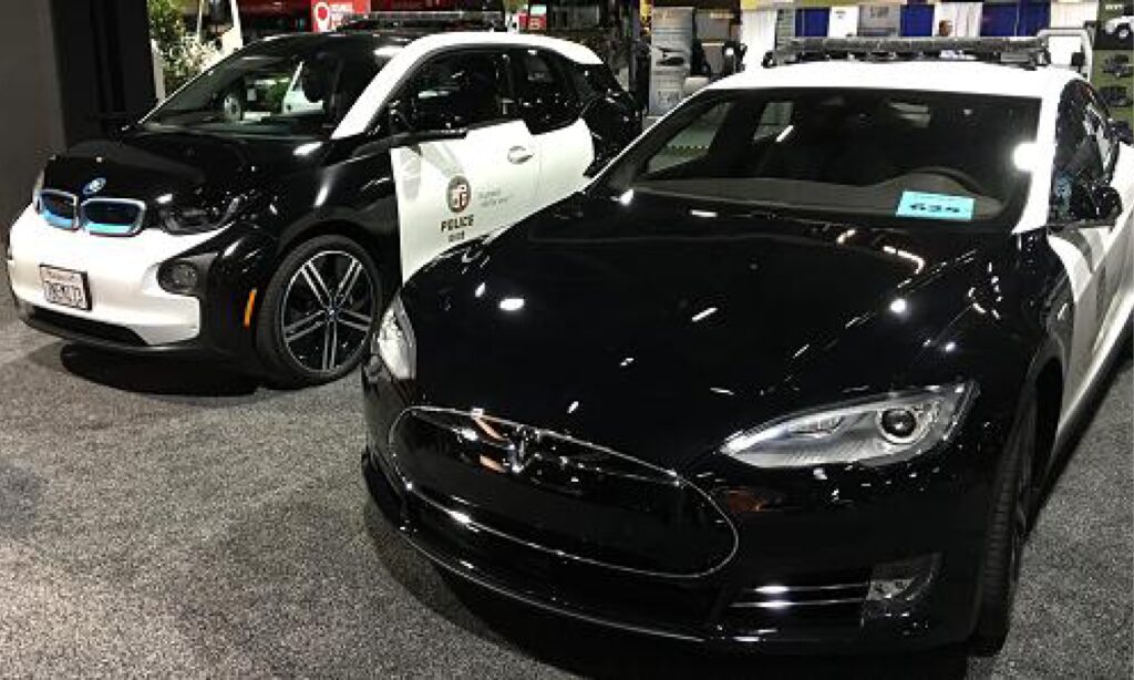 En polisbil och en Tesla Model S parkerade i en parkeringsplats. (AI text)