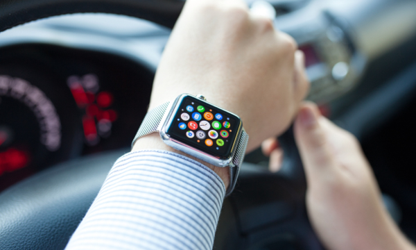 En kvinna kör en bil och har en Apple Watch på sitt armband. (AI text)