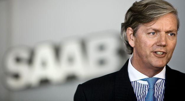 En man i kostym och slips talar till en kamera. (AI text)