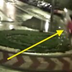 En bil kör nerför en gata i regnet. (AI text)