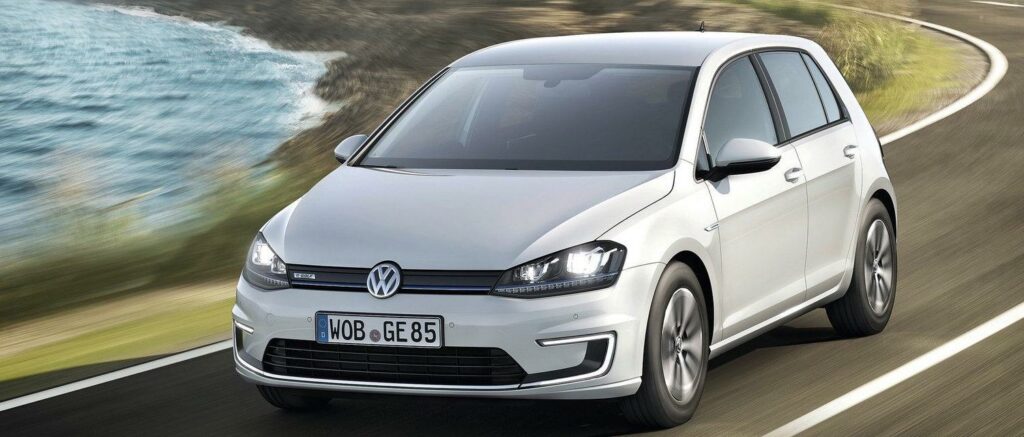 En Volkswagen e-Golf kör längs en väg. (AI text)