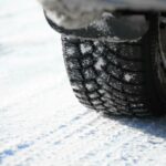 En bil står parkerad på en snöig väg. (AI text)