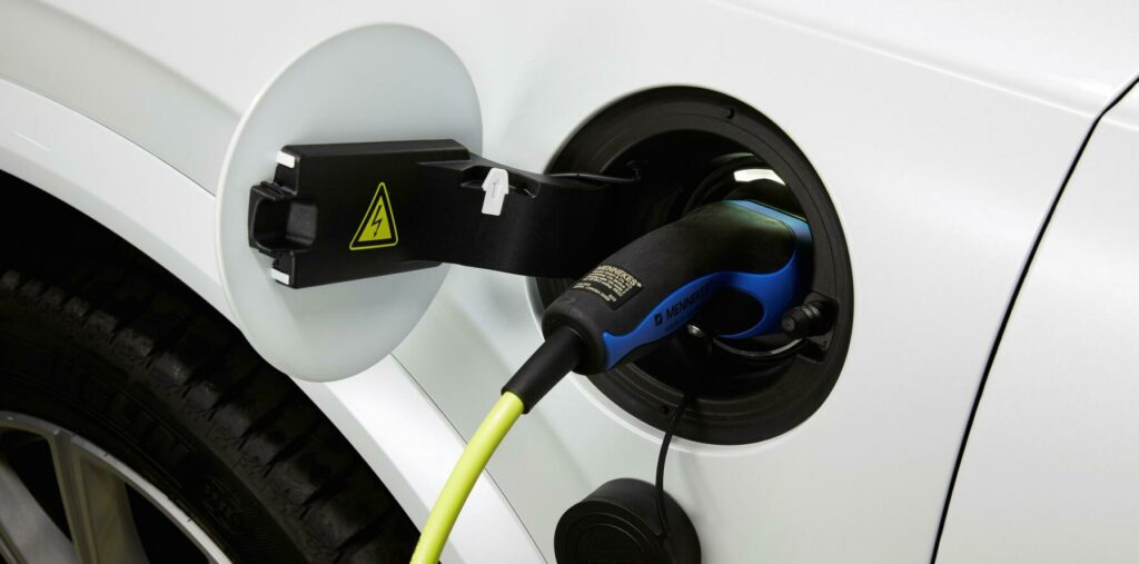 En vit bil är uppkopplad till en elladdare. (AI text)