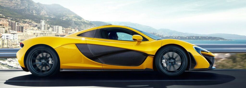 En gul sportbil kör på en väg med utsikt över havet. (AI text)