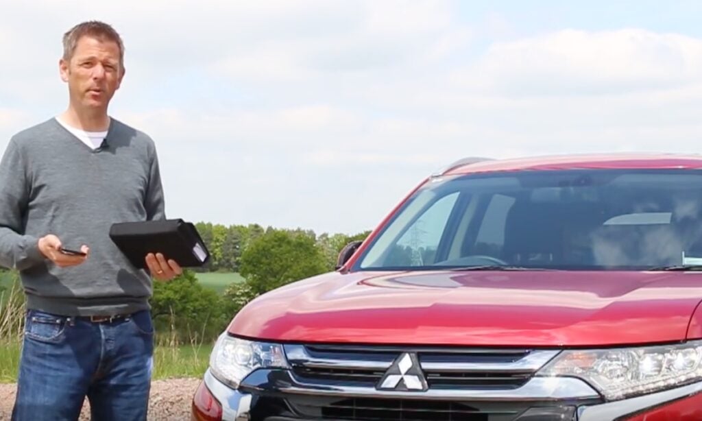 En man står bredvid en röd bil. (AI text)