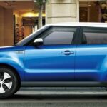 En blå Kia Soul parkerad framför ett byggnad. (AI text)