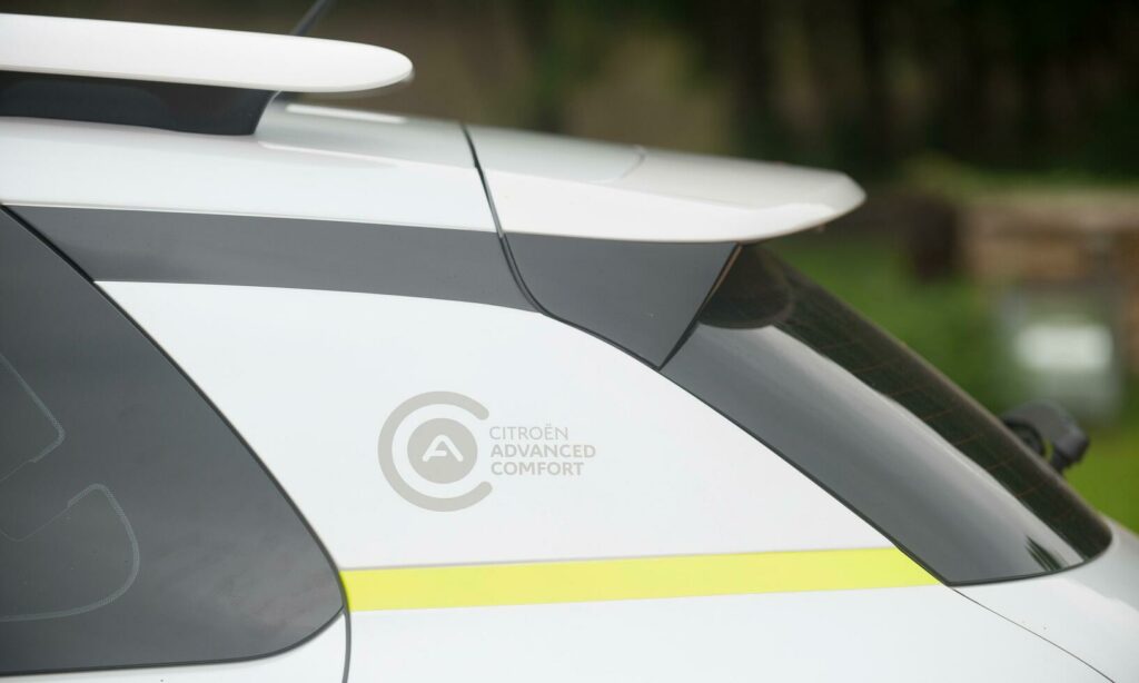 En vit bil med ett gult och vitt logotyp. (AI text)