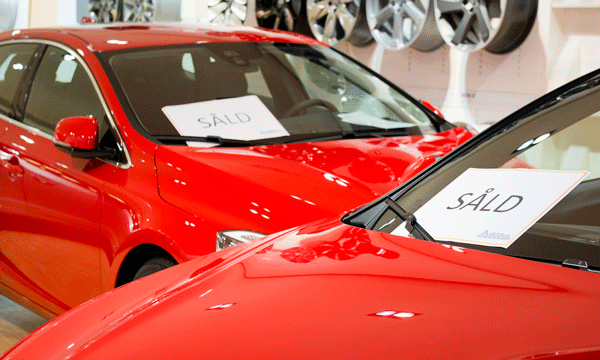 En röd bil visas upp i en utställningslokal. (AI text)