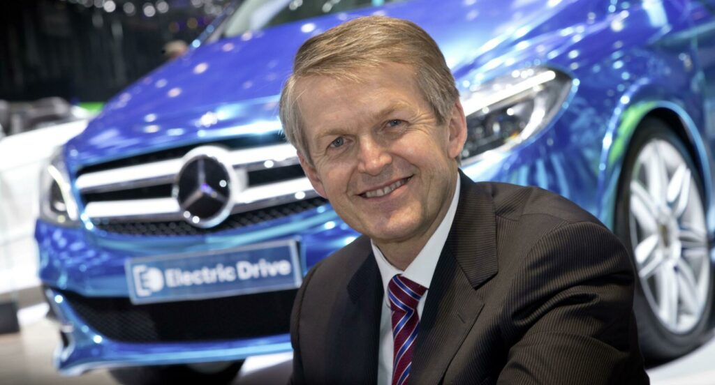 En Mercedes-Benz-exekutiv står tillsammans med en bil. (AI text)