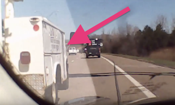 En polisbil kör längs vägen med en rosa pil som pekar mot den. (AI text)