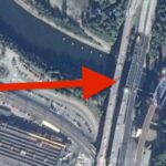 En bil är parkerad på en bro över en flod. (AI text)