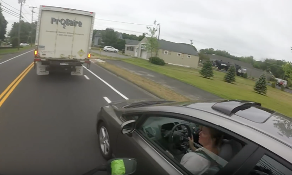 En bil kör ner en väg med en lastbil bakom den. (AI text)