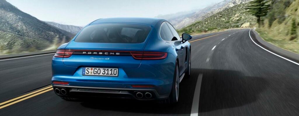 En blå Porsche Macan kör nerför en bergsväg. (AI text)