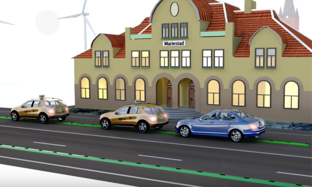 En bil kör nedför en gata med vindkraftverk bakom den. (AI text)