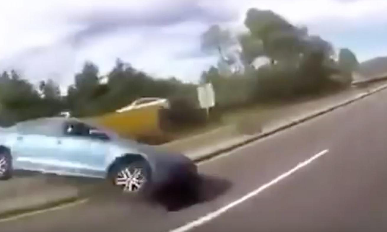 En bil ligger uppochnersad på en väg. (AI text)