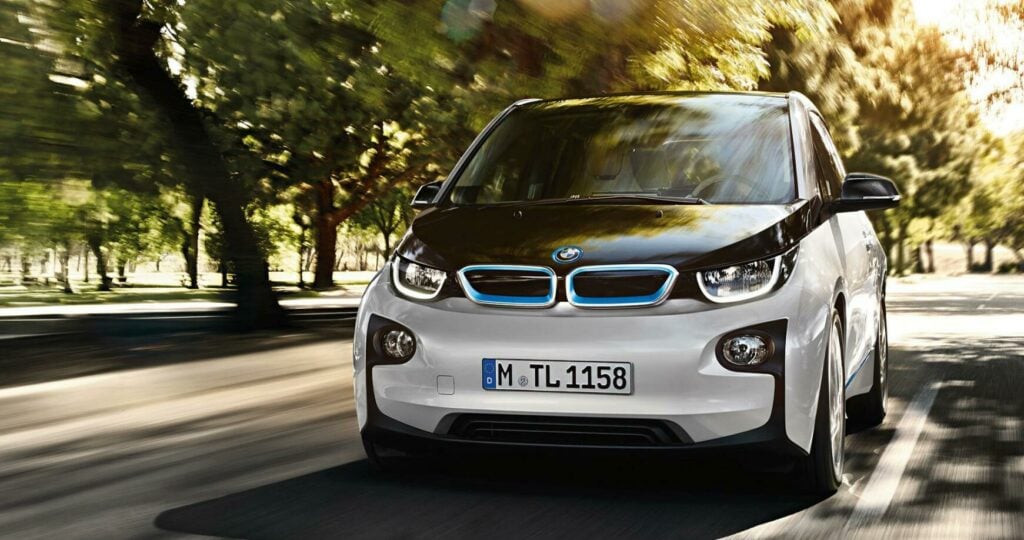 En BMW i3 kör på en väg. (AI text)